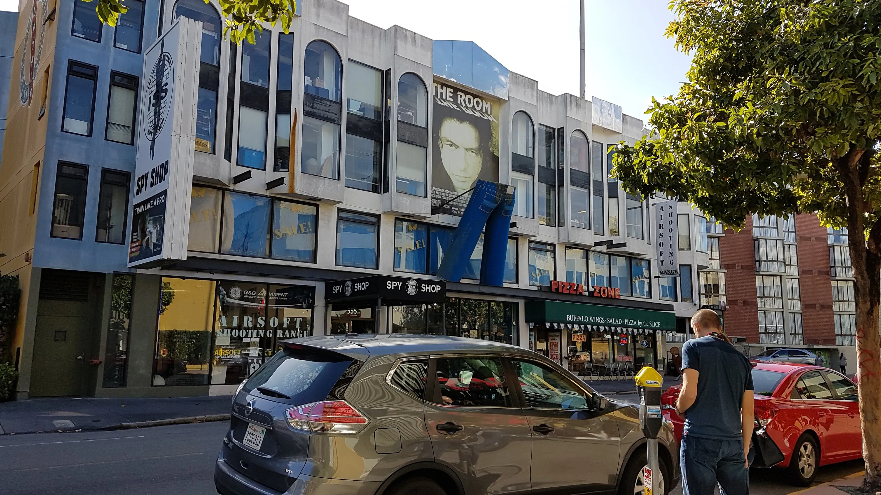 A building with a large poster for The Room and a scuplture of blue jeans