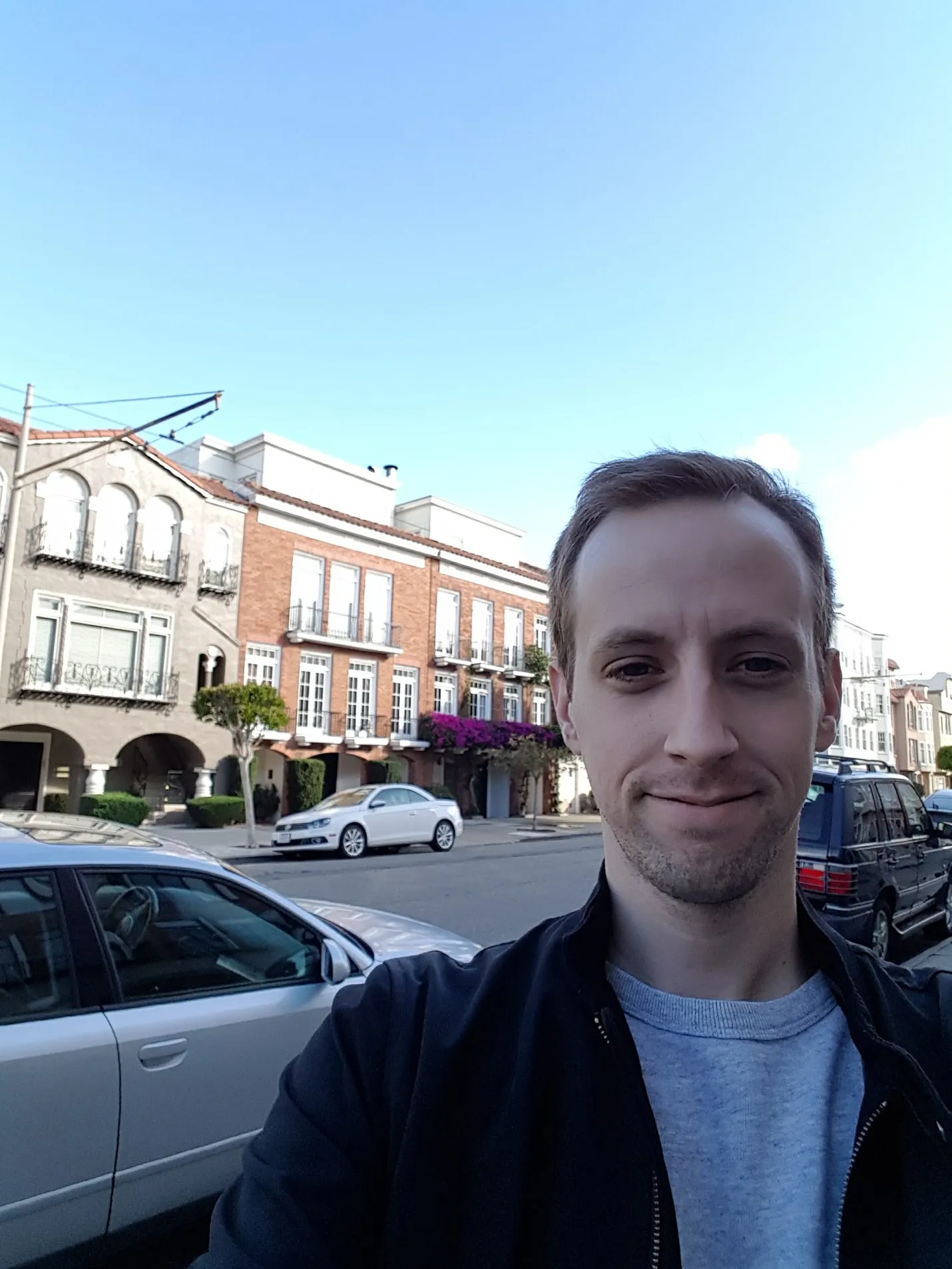 The author with a brick house on Broderick Street in the background